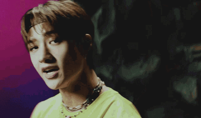 a close up of a person 's face with a pink background and a yellow shirt