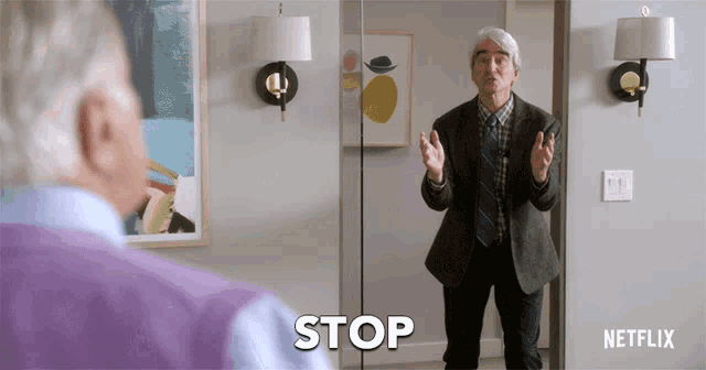 a man in a suit is standing in front of a mirror with the word stop on it