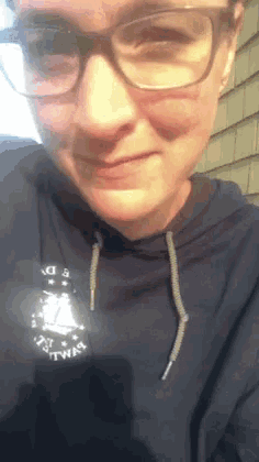 a woman wearing glasses and a hoodie that says ' i 'm a twin ' on it