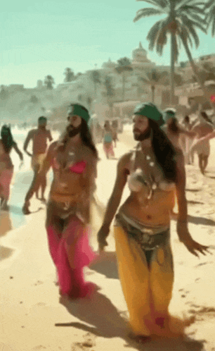 a man with a beard is walking with two women on the beach