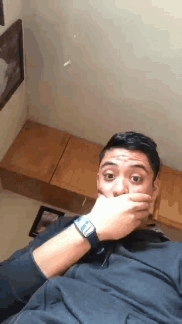 a man with a watch on his wrist is covering his mouth with his hand