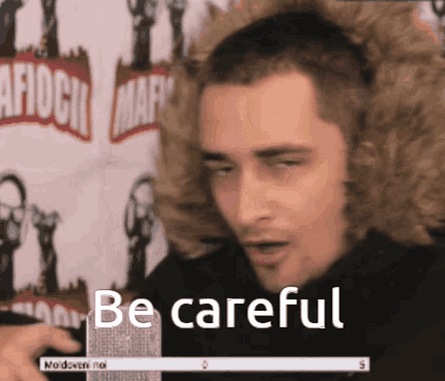 a man in a fur hooded jacket says be careful in front of a microphone