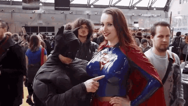 a man in a batman costume points to a woman in a superman costume