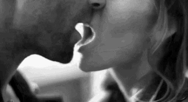 it is a black and white photo of a man and woman kissing .