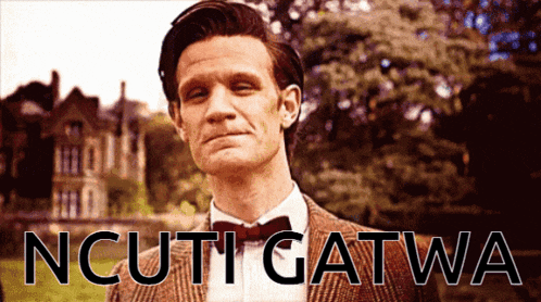 a man in a suit and bow tie is standing in front of a sign that says " ncuti gatwa "