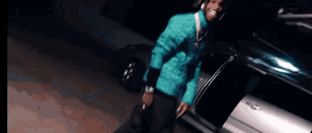 a man in a blue jacket is standing next to a car with the door open .