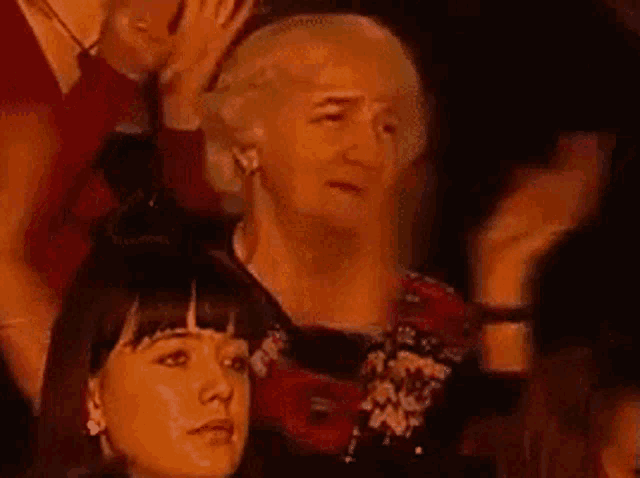 a group of women are clapping in a dark room .