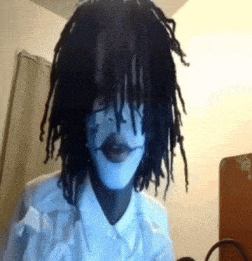 a person with dreadlocks wearing a white shirt and a white mask