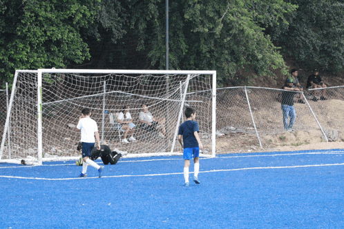 a group of soccer players are playing on a field with a fence behind them
