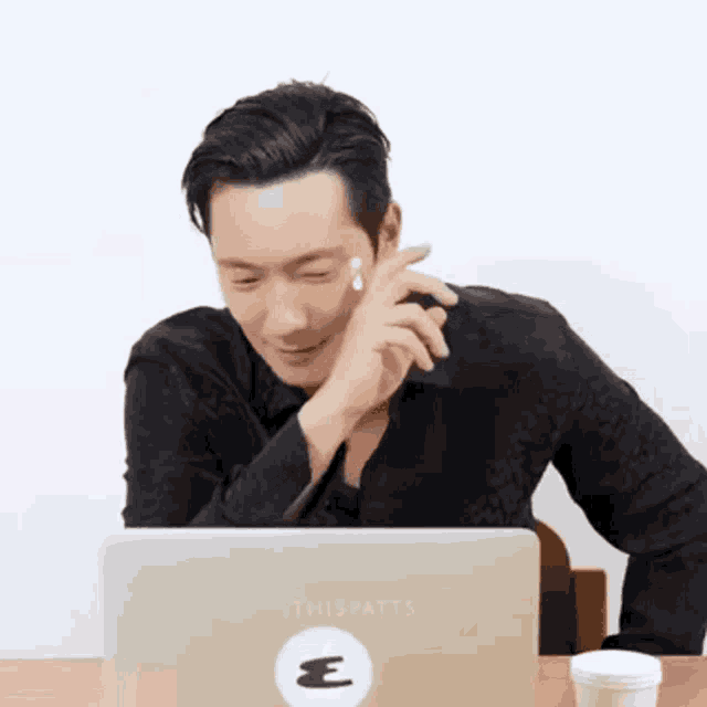 a man is sitting at a table with a laptop and a cup of coffee .