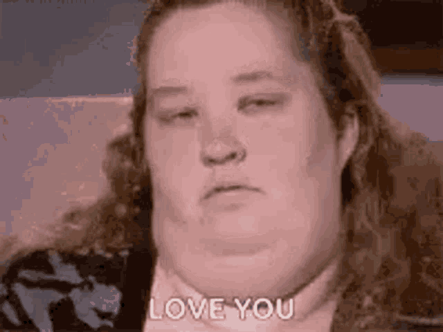 a woman is sitting on a couch and making a funny face while saying `` i love you '' .