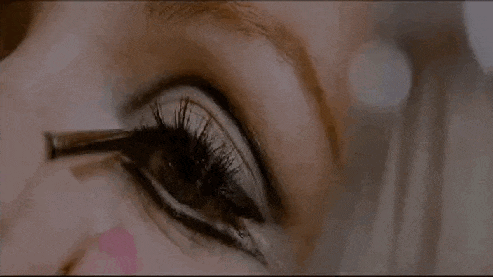 a close up of a woman applying makeup to her eyes .