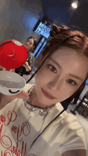 a woman is taking a selfie while holding a small red bowl
