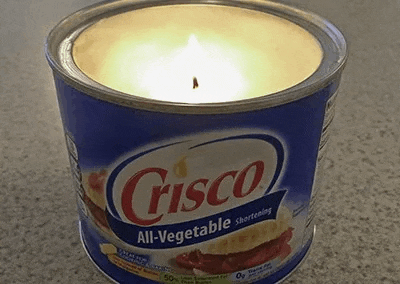 a candle is sitting inside of a can of vegetable shortening .