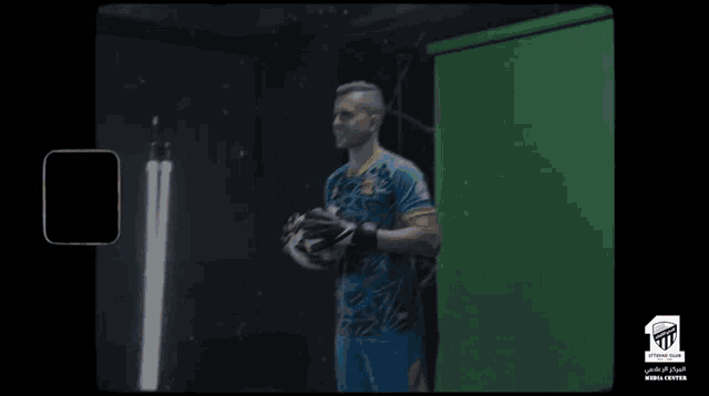 a man holding a soccer ball in front of a green background