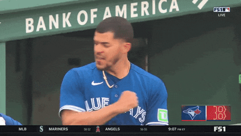 a blue jays player stands in front of a bank of america banner