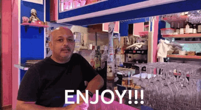 a man behind a bar with the words enjoy written on the bar