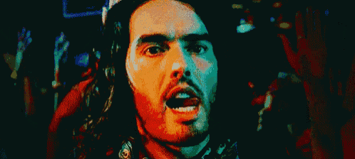 a man with long hair and a beard is looking at the camera with his mouth open