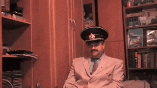 a man in a suit and hat is sitting at a desk