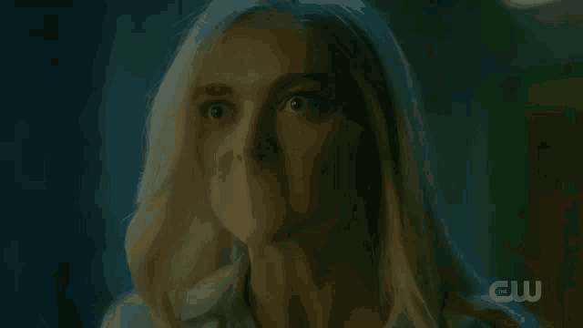 a woman in a dark room with a cw logo in the background