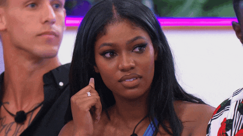 a woman with a diamond ring on her finger is sitting in front of two men