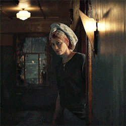 a woman with a towel on her head is standing in a dark hallway