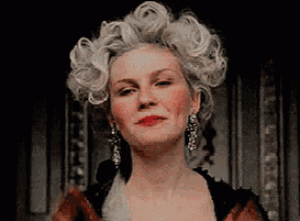a woman with a wig on her head and earrings is looking at the camera .