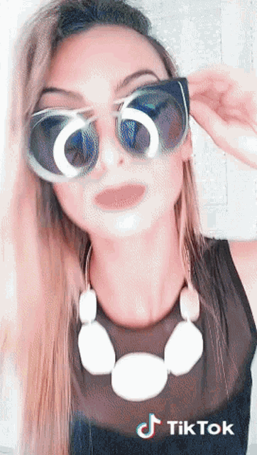 a woman wearing sunglasses and a necklace has tiktok written on the bottom of her photo