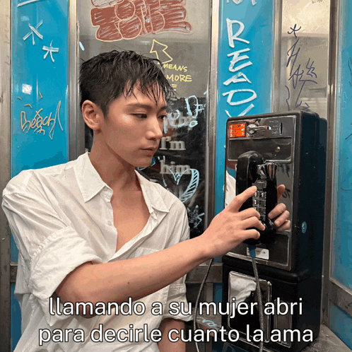 a man in a white shirt is talking on a pay phone with a sign that says ready