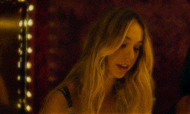 two women are standing next to each other in a dark room and one is touching her hair