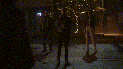 a group of people are dancing in a dark room with purple lights