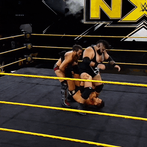 wrestlers in a ring with a n on the wall behind them