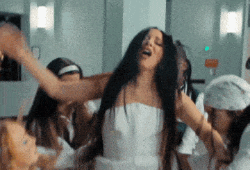 a woman in a white dress with her arms outstretched is surrounded by other women .