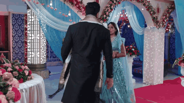 a man and a woman are standing on a red carpet in a room decorated for a wedding .