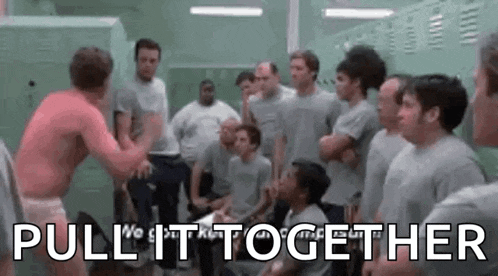 a group of men are standing in a locker room and one of them is wrestling another man .