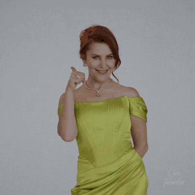 a woman in a green dress is giving a thumbs up sign