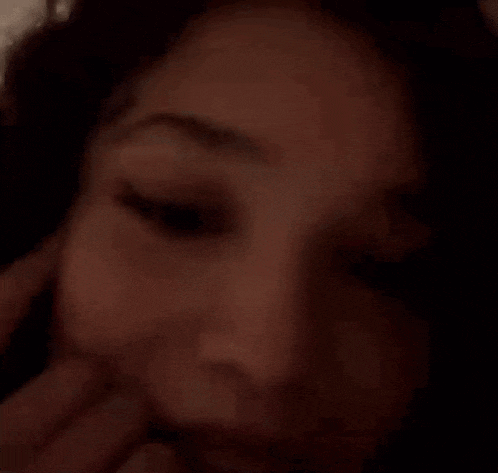 a close up of a woman 's face with her hand on her face and smiling .