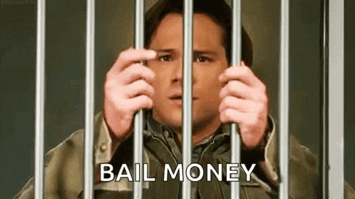 a man is behind bars with the words `` bail money '' written on the bars .