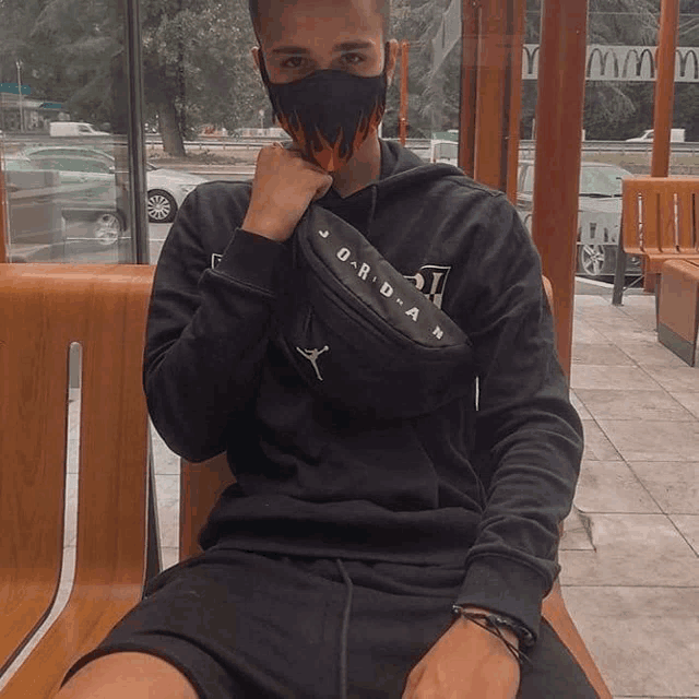 a man wearing a mask and a jordan waist bag