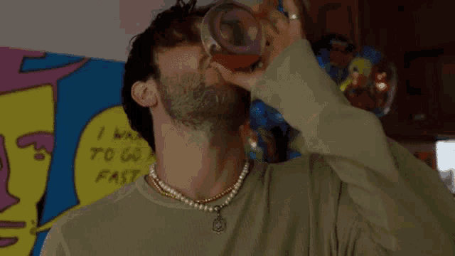 a man wearing a pearl necklace is drinking a drink from a bottle .