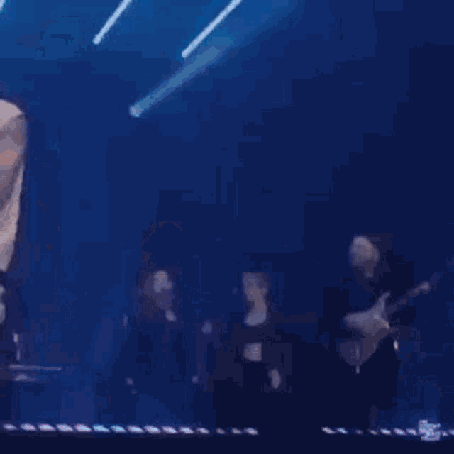 a woman in a crop top and hat is dancing on a stage while a man sings into a microphone .