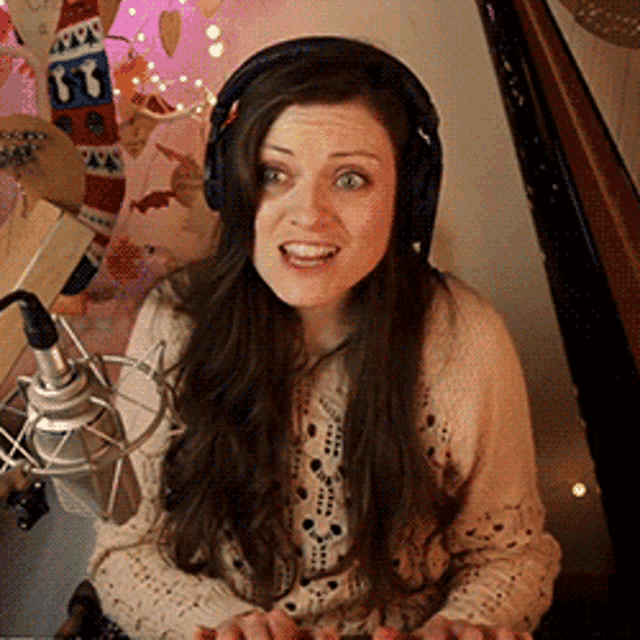 a woman wearing headphones is smiling in front of a microphone and a christmas tree
