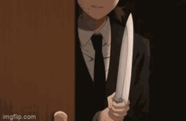 a man in a suit and tie is holding a large knife