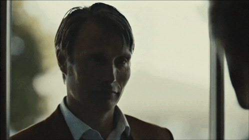 a man in a suit and tie is looking out a window .