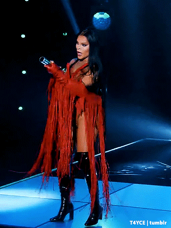 a woman in a red and black outfit is holding a microphone on a stage
