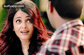 a woman with red hair is looking at a man with a plaid shirt .