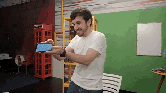 a man holding a phone in front of a phone booth that says telephone