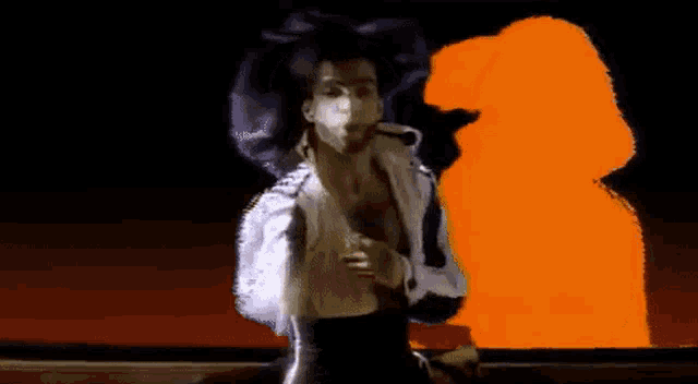 a man in a white shirt is standing in front of a purple and orange background .