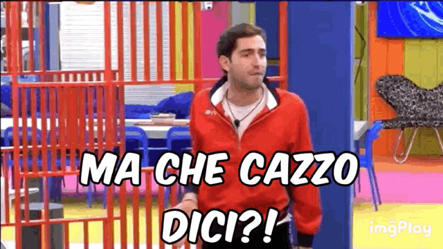 a man in a red jacket is standing in a room and says ma che cazzo dici ?