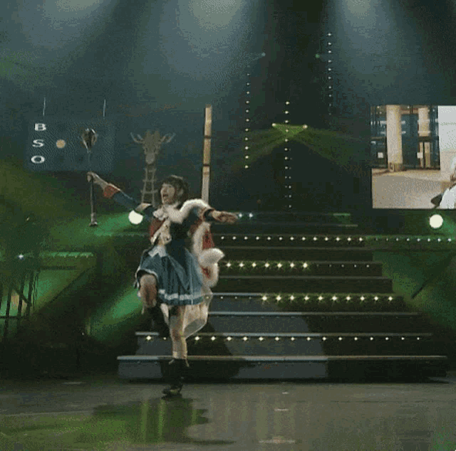 a woman is dancing on a stage in front of a large screen